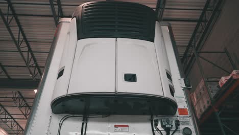 low angle of a front reefer trailer sitting in a repair shop of a truck and trailer maintnance building