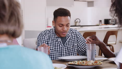 Close-up-of-you-black-man-sitting-at-dinner-table-with-his-family,-holding-hands-and-saying-grace