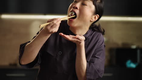 asian woman chef eating sushi with chopsticks