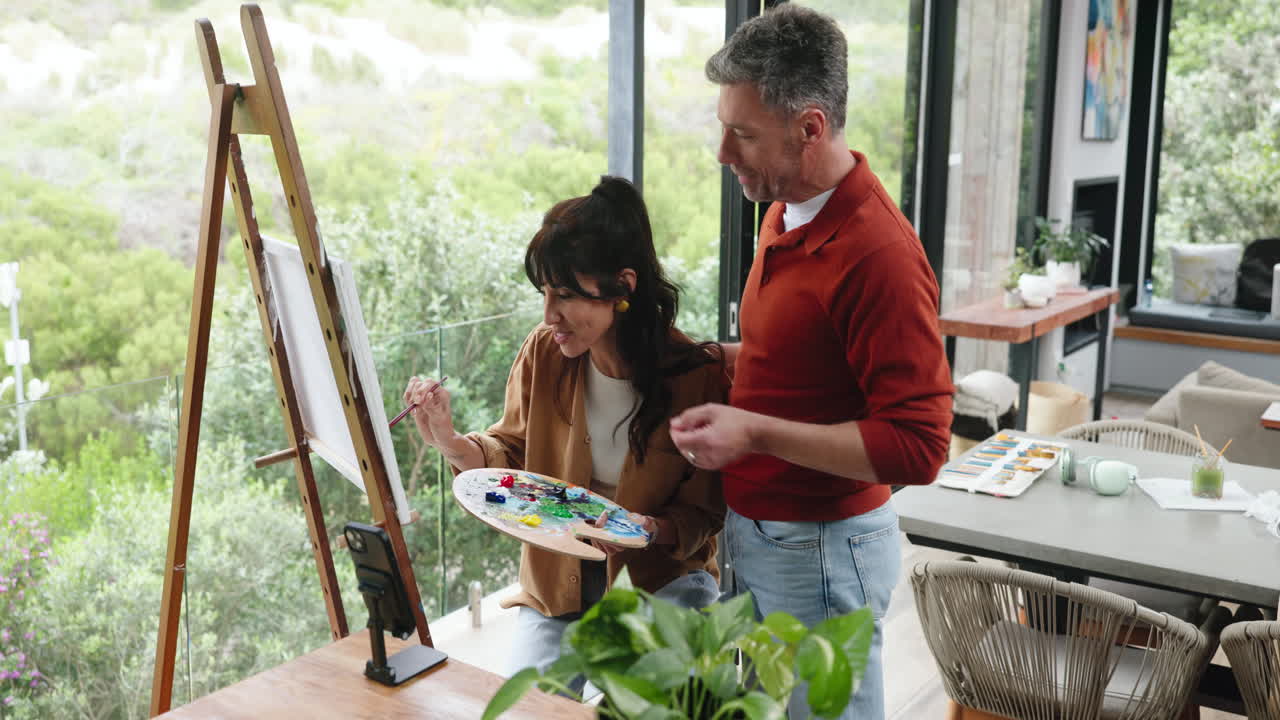 Pareja feliz creando arte en un caballete en casa