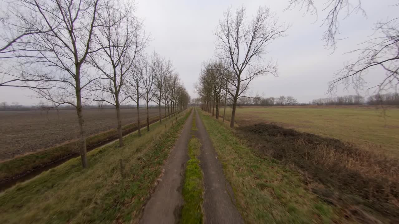 Fast aerial shot following a road on a Dutch dyke during winter. Medium to high angle