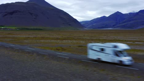 car driving past beautiful mountain scenery in hoffell area in southern iceland - aerial shot