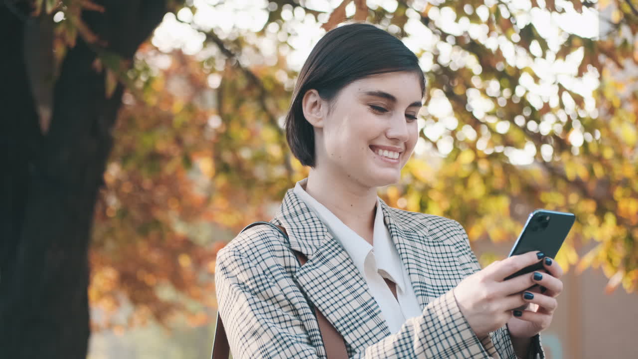 una mujer de negocios elegante usando un teléfono inteligente al aire libre.