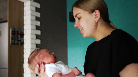 mother is calming down her tiny newborn baby. loving mom waving son in her hands and then presses him to her cheek.