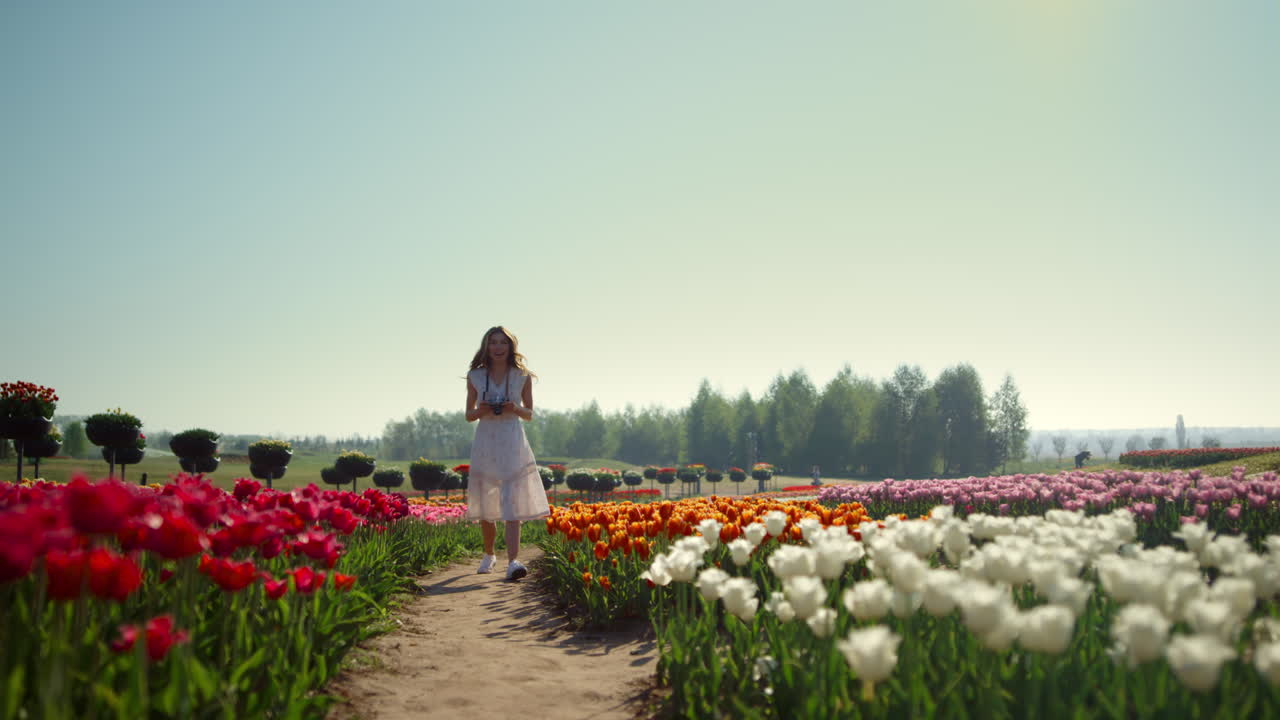 mujer hermosa con cámara en el jardín de tulipanes. chica positiva tomando fotografías