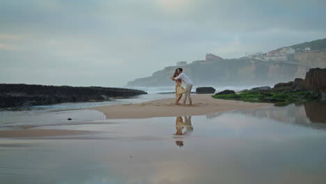 Sensual-couple-embracing-beach-at-cloudy-sky.-Man-twirling-woman-dance-vertical