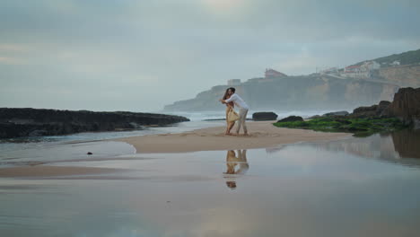 sensual couple embracing beach at cloudy sky. man twirling woman dance vertical