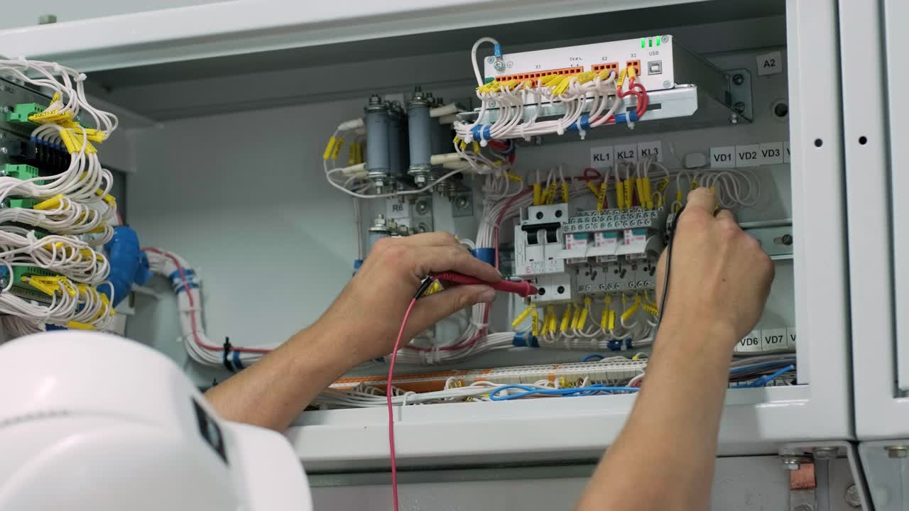 el ingeniero eléctrico que trabaja comprueba la tensión de corriente eléctrica y la sobrecarga en la parte delantera del gabinete del centro de carga o de la unidad de consumo para el mantenimiento en la sala principal del sistema de distribución de energía.