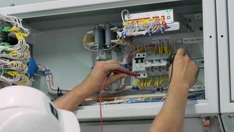 electrical engineer working check the electric current voltage and overload at front of load center cabinet or consumer unit for maintenance in main power distribution system room.