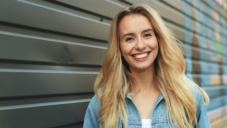 close-up view of charming young blonde woman with blue eyes looking and smiling at the camera