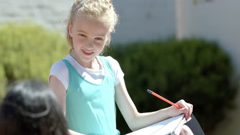 caucasian girl with blonde hair is drawing outdoors in school