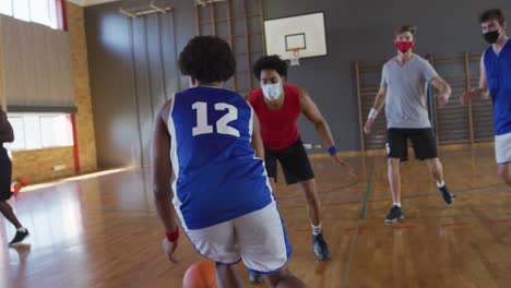 equipo de baloncesto masculino diverso y entrenador jugando partido, usando máscaras faciales