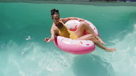 woman relaxing on donut float in swimming pool, enjoying sunny day, copy space