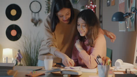 mother and daughter studying and sharing cookies at night