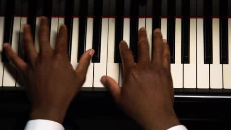 top view of male hands playing the grand piano. the african american touches the black and white keys with his fingers to create the rhythm of the melody. close up black hands of a male pianist