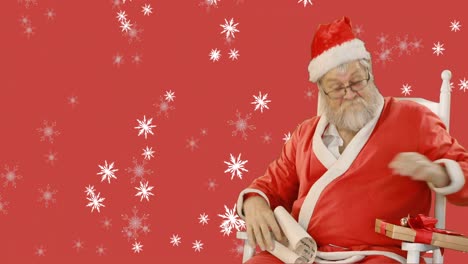 copos de nieve cayendo sobre santa claus con regalos de navidad contra un fondo rojo