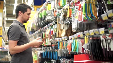 hombre comprando utensilios de cocina en un supermercado