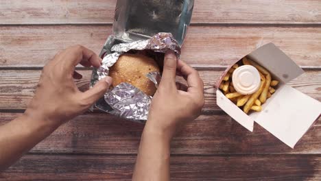 persona comiendo una hamburguesa y papas fritas