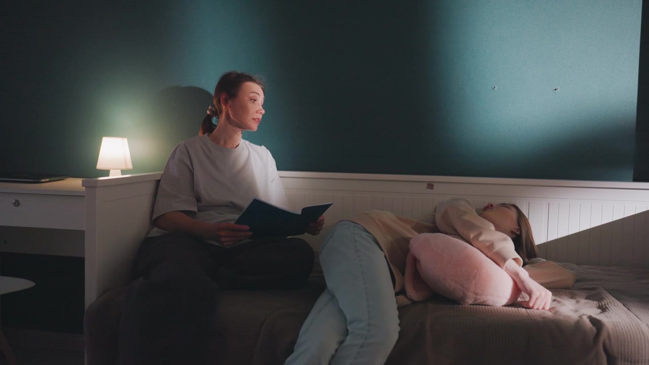 Evening bedroom reading with white tutor sharing bedtime story to teen under soft lamp glow reader holds open book while listener curls around plush pillow, gentle voice and whisper narration create
