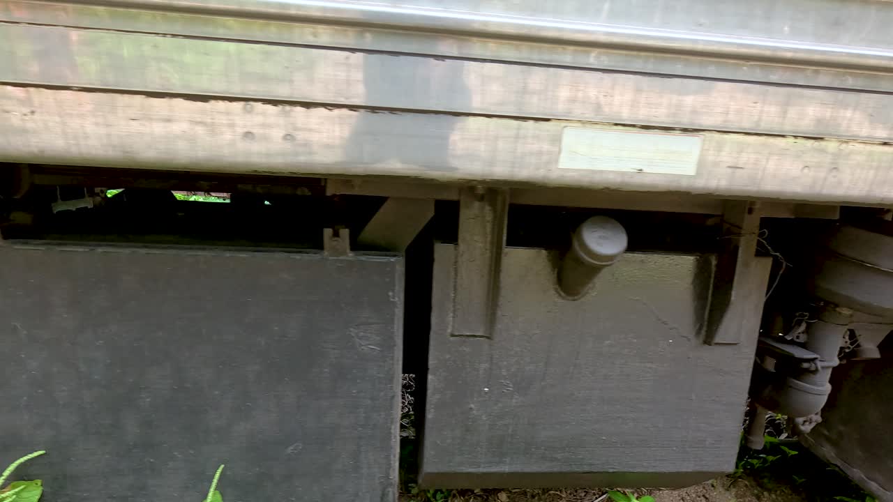 Close-up views of a train's undercarriage components in Kanchanaburi, Thailand, highlighting mechanical details and lush greenery