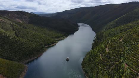 Aerial-view-of-a-boat-sailing-through-some-beautiful-pine-wood-forest-and-valleys