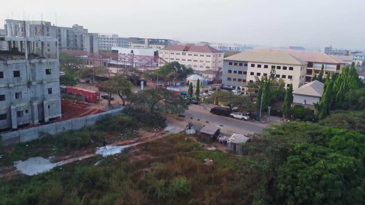 Drone che sorvola attrezzature pesanti in un cantiere urbano e si inclina verso l'alto per mostrare la skyline di Abuja, Nigeria.