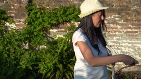 female gardener watering home-grown plants in garden vegetable patch