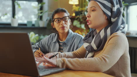 two immigrant female students using laptop and doing homework in classroom