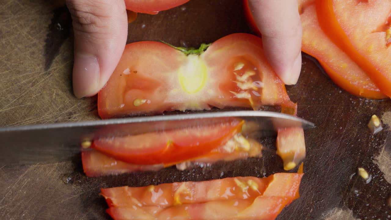 Slicing fresh tomato Solanum lycopersicum close-up, March kitchen