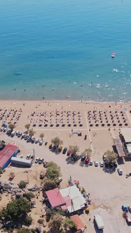 vista aérea de una playa ocupada con paraguas y agua azul clara