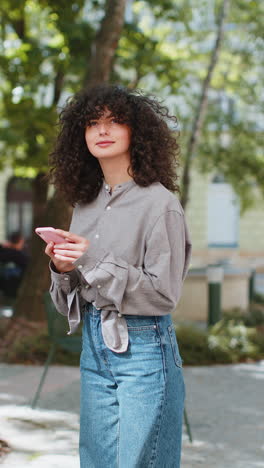 Tourist-young-curly-hair-woman-using-smartphone-typing-text-messages-looking-for-search-a-way-on-map