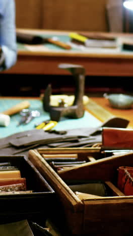 mid-section of craftswoman stitching a piece of leather