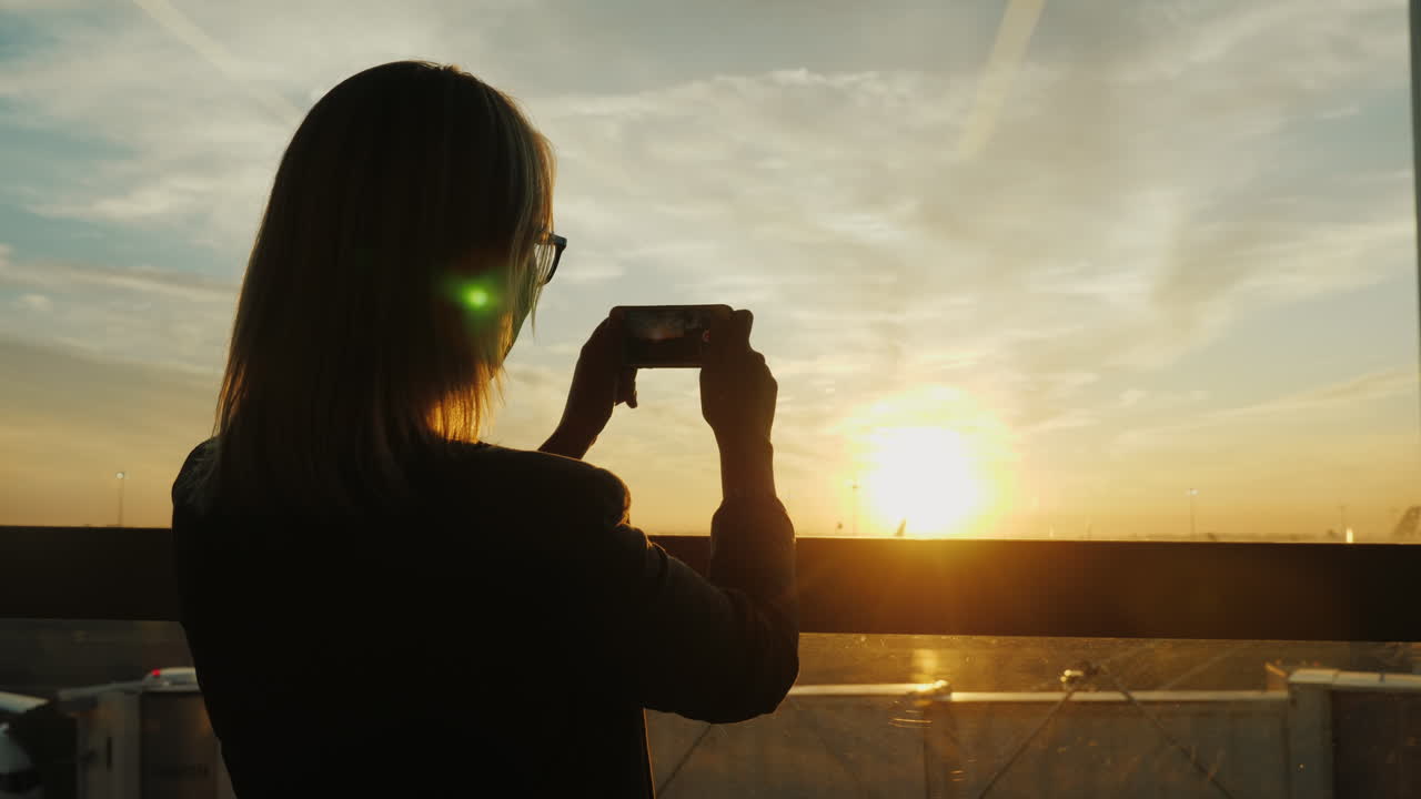 여자는 일몰 비행장 사진을 찍는다