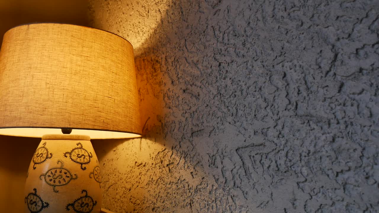 Warm Light from a Decorative Table Lamp Illuminates a Textured Wall