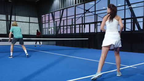 playing padel tennis on indoor court, two players focusing on intense match