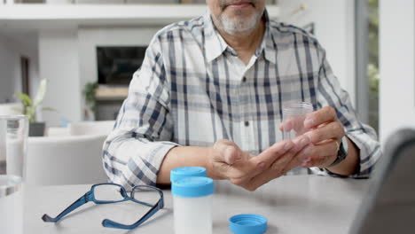 un hombre de dos razas con medicamentos haciendo una llamada de video en tableta con un médico, en cámara lenta.