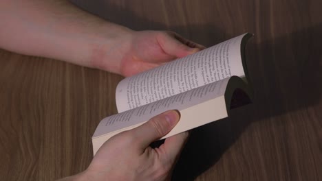 man holding a book at a table about wealth learning about investing