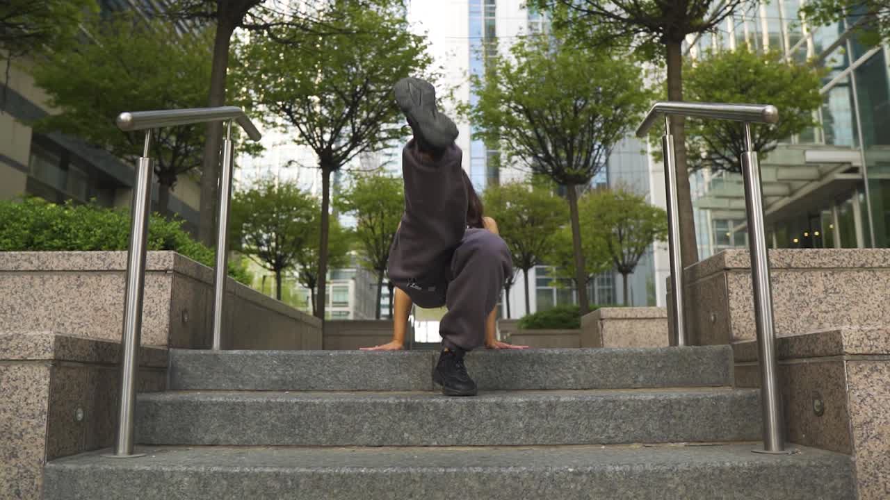 시내 계단에 앉아 웃고 있는 음악을 즐기며 공연하는 유연하고 멋진 활동적인 댄서