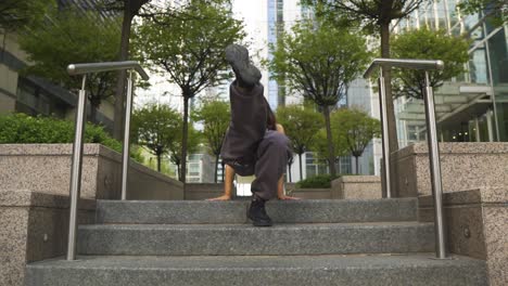 bailarina activa flexible y fresca actuando mientras se sienta en los escalones en el centro disfrutando de la música sonriendo, luego se da la vuelta y levanta las caderas por encima de su torso a cámara lenta