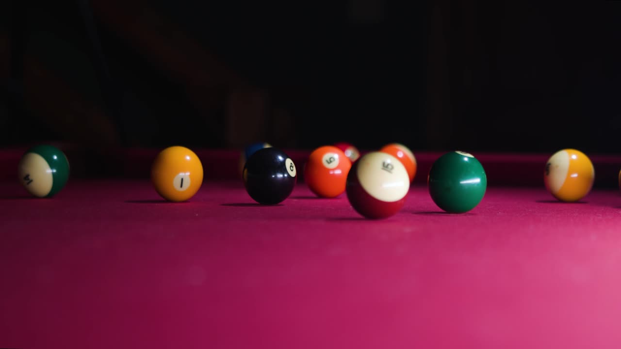 Slow motion Man hits cue ball and breaks ball rack on the pool table