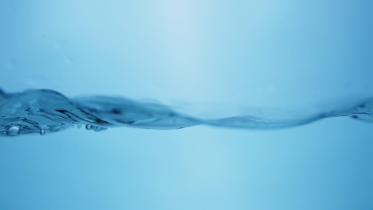 파란색 배경에 물로 가득 찬 용기에 작은 물방울과 파동을 일으키는 물 어리