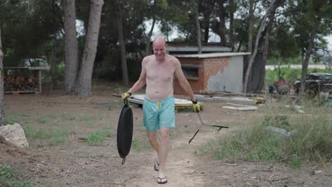 happy man carrying a large cooking pan and tripod outdoors
