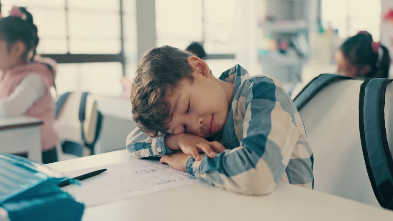 Tired, sleeping and child at desk in classroom