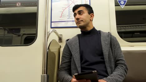 man reading tablet in subway car