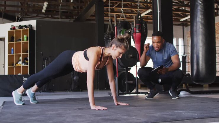 Video of african american male trainer motivating caucasian woman for doing push ups