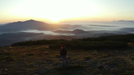 Un-Excursionista-De-Pie-Sobre-Una-Roca-En-La-Cima-De-Una-Montaña-Durante-El-Amanecer