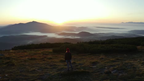 a hiker standing on a rock on top of a mountain during sunrise