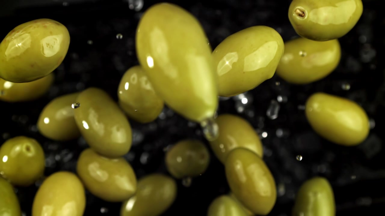Olive verdi che cadono in super slow motion con schizzi d'acqua.
