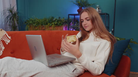 young woman using credit bank card and laptop, transferring money, purchases online shopping