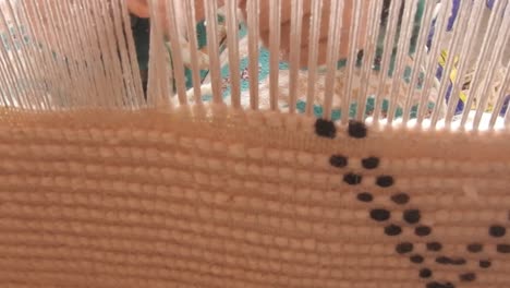 close up on a moroccan girl weaving a carpet with a manual waving machine, carpet weaving , needlework , morocco